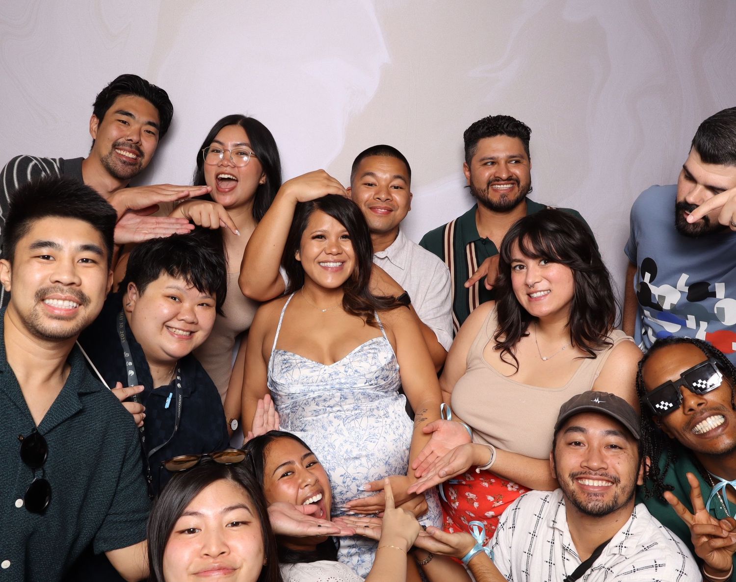 A diverse group of smiling friends posing together for a fun photo booth picture at a celebration event.