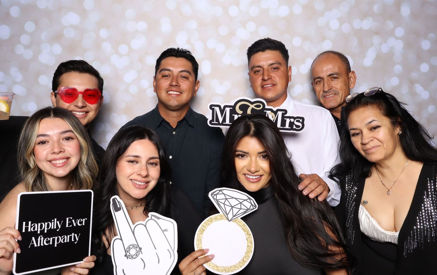 A group poses together at a party with festive bokeh lights sparkling in the background.