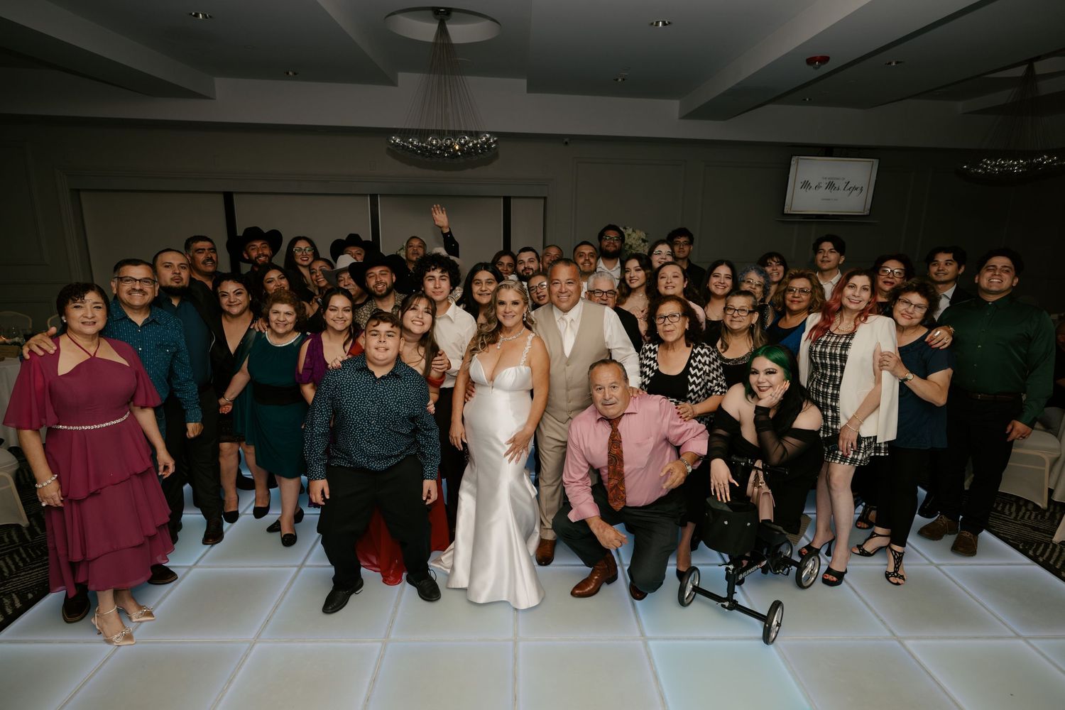 Large group photo of wedding guests posing together in a reception hall.