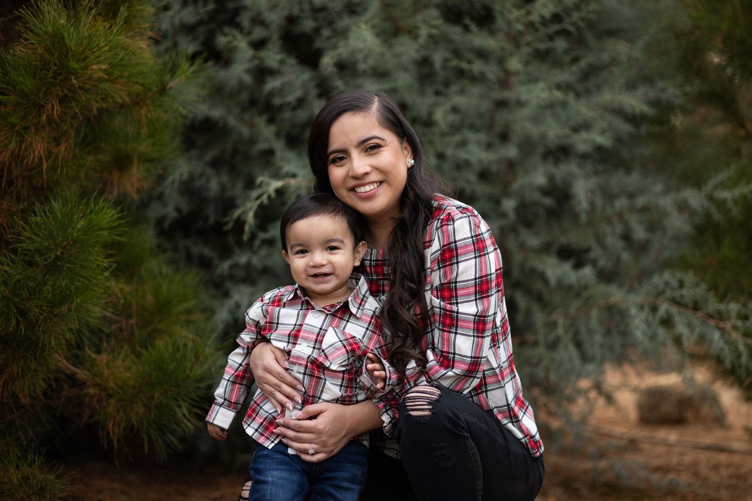 Family in plaid shirts sharing joyful moments during outdoor photo session.