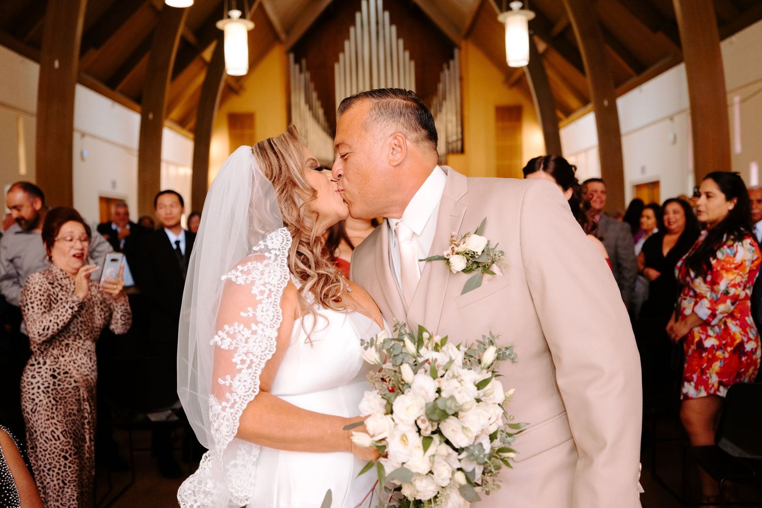 Wedding ceremony taking place in a beautiful chapel with wooden beams and cathedral ceiling.
