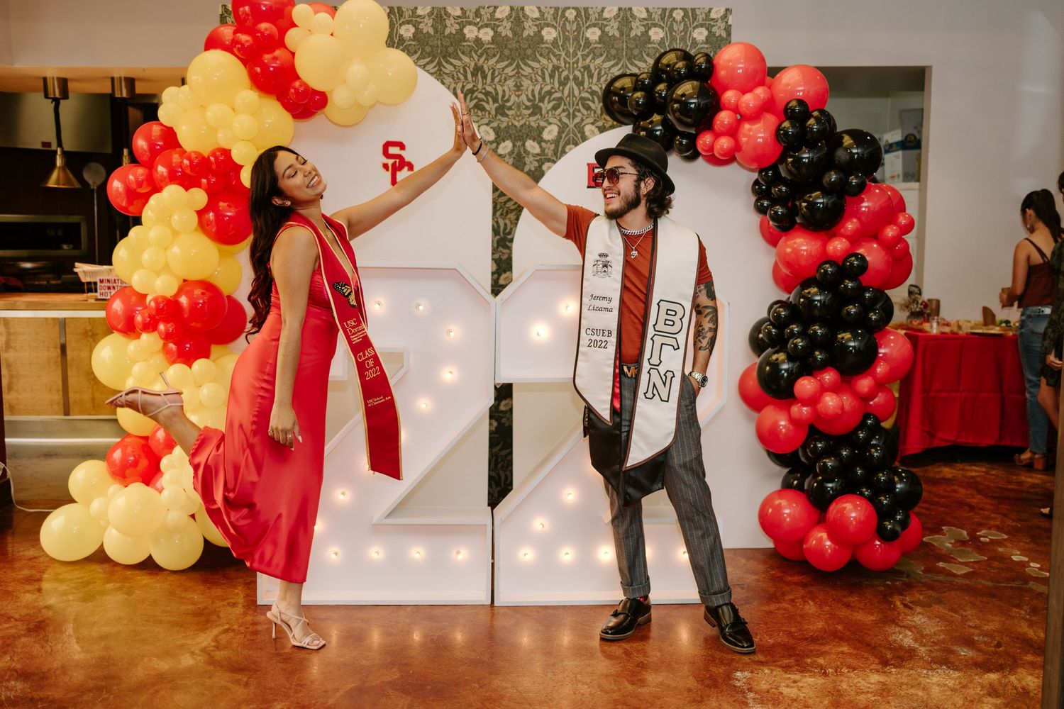 Balloon arch with red, yellow and black balloons frames illuminated numbers.