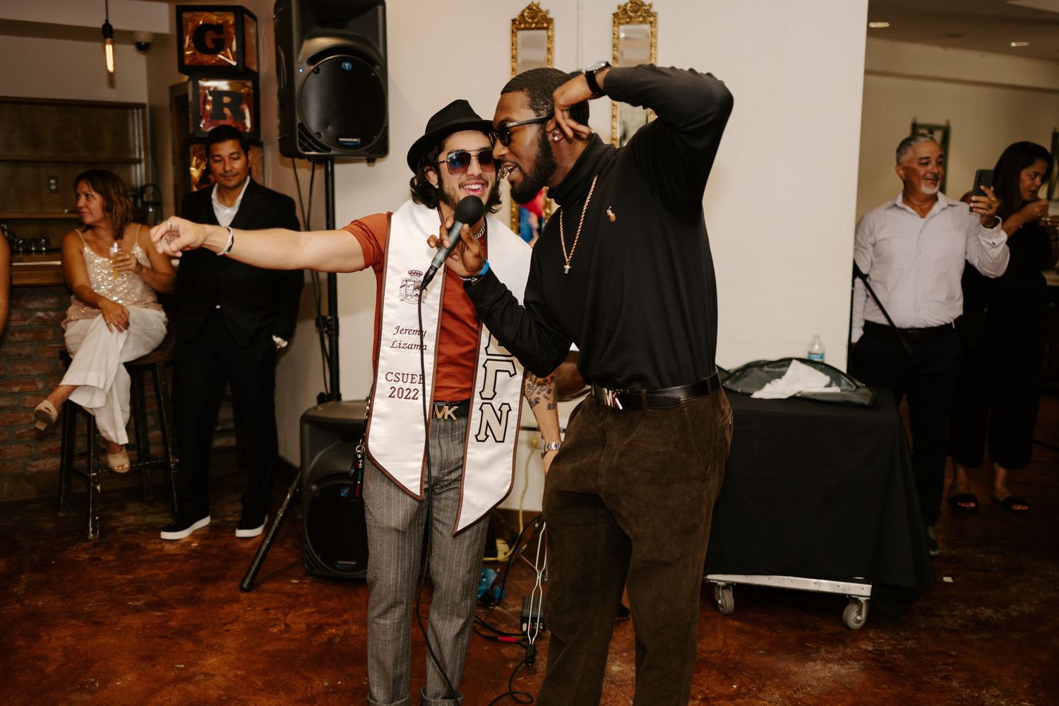Two guests dancing and singing together at an indoor celebration event.