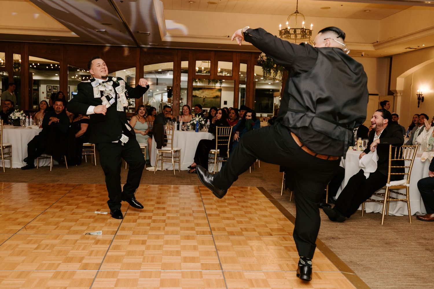 Energetic groomsmen performing high kicks while dancing at a wedding reception.