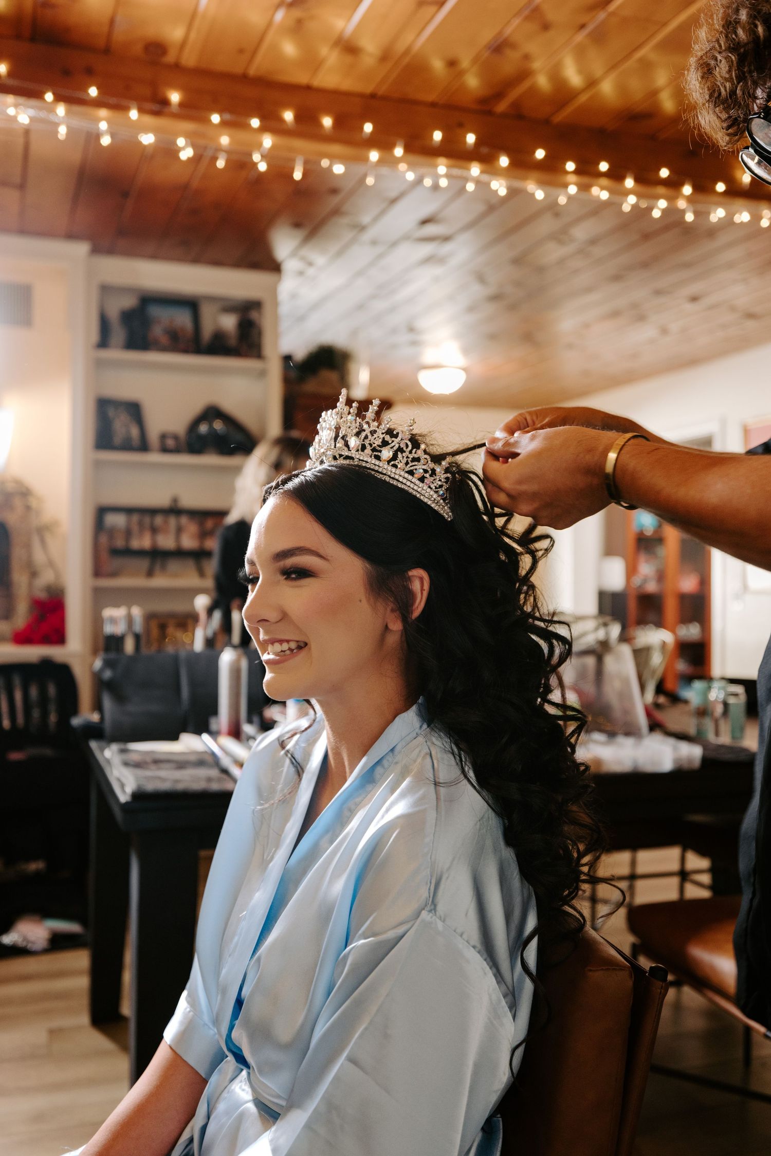 Getting ready for a special occasion with a sparkling tiara being placed under warm string lights.