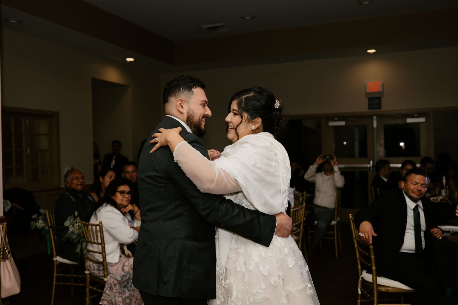 Wedding reception dance floor filled with guests celebrating in dimly lit venue.