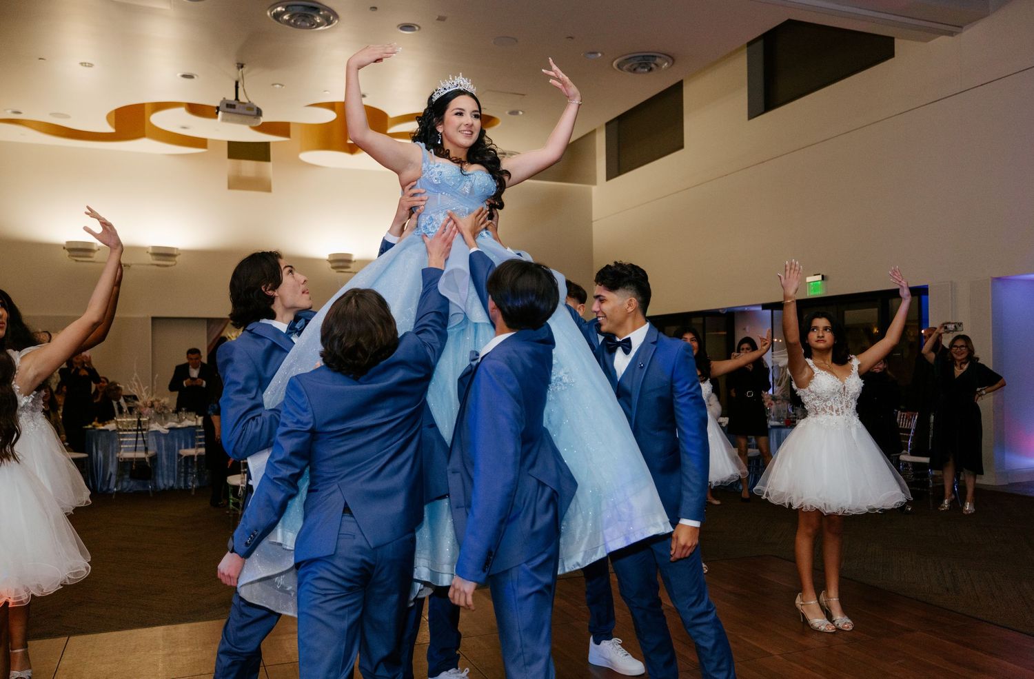 Celebratory moment with group in blue suits lifting someone up during a party.