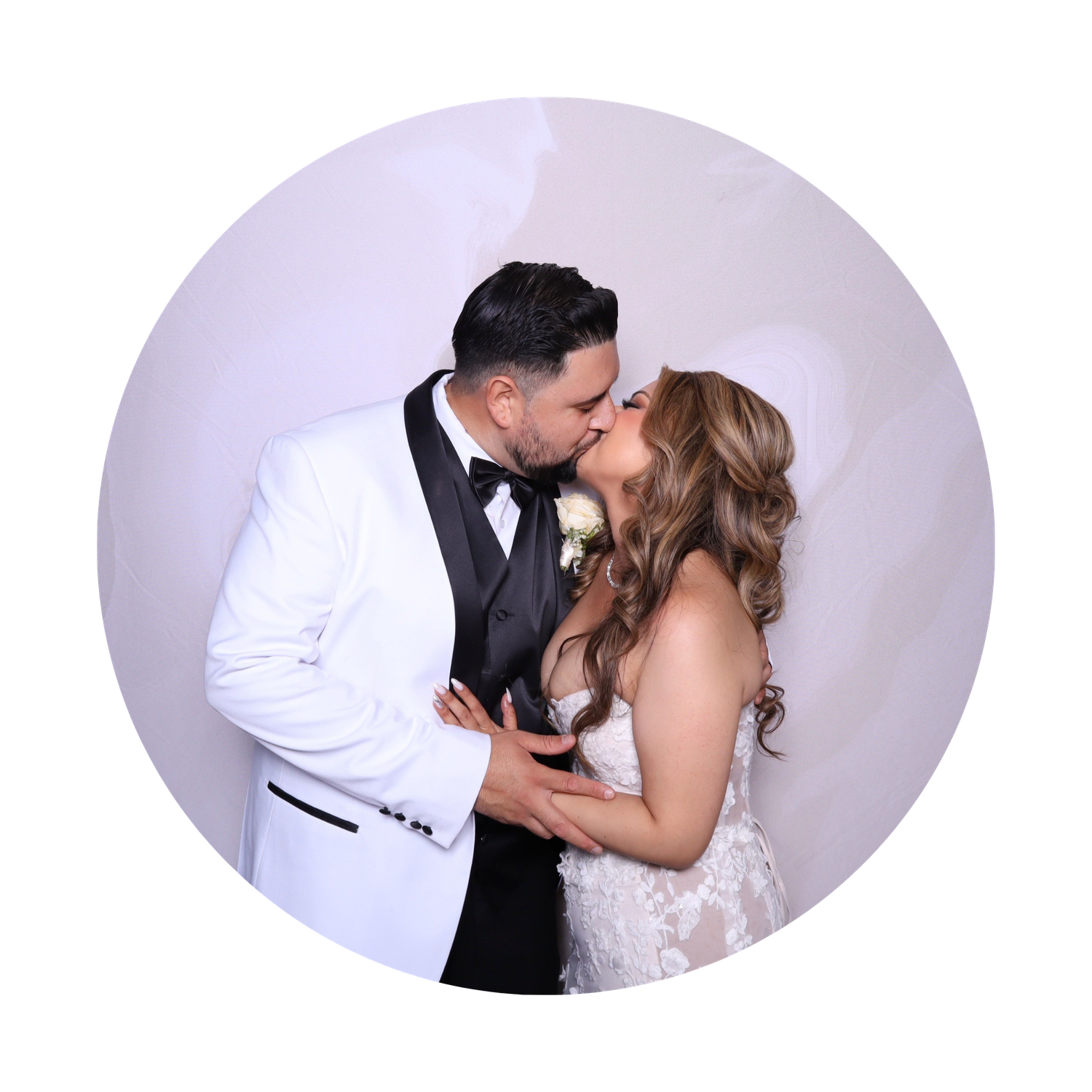 Bride and groom sharing a romantic kiss, groom in white tuxedo, bride in lace wedding dress.