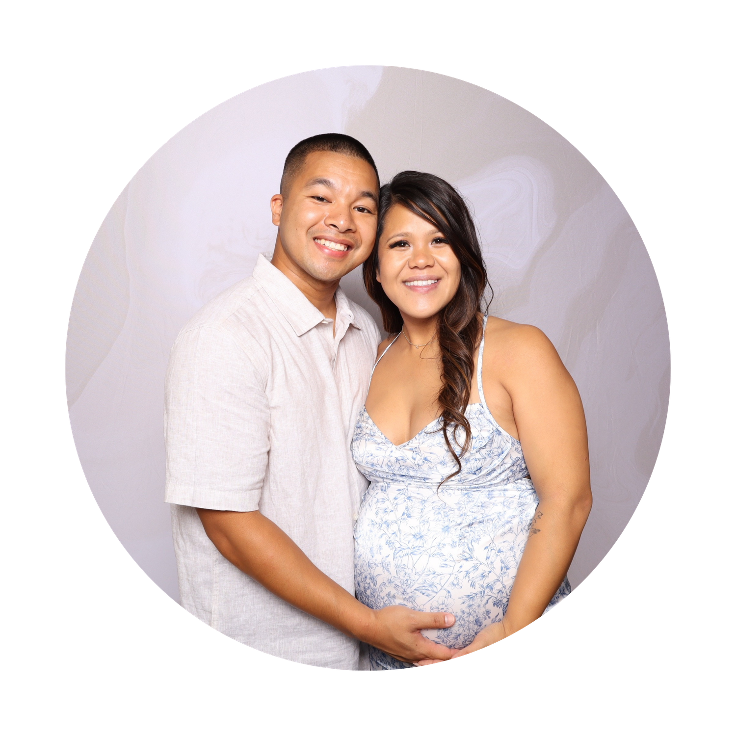 Happy couple posing for a maternity photo, woman in floral dress cradling baby bump, man smiling beside her.