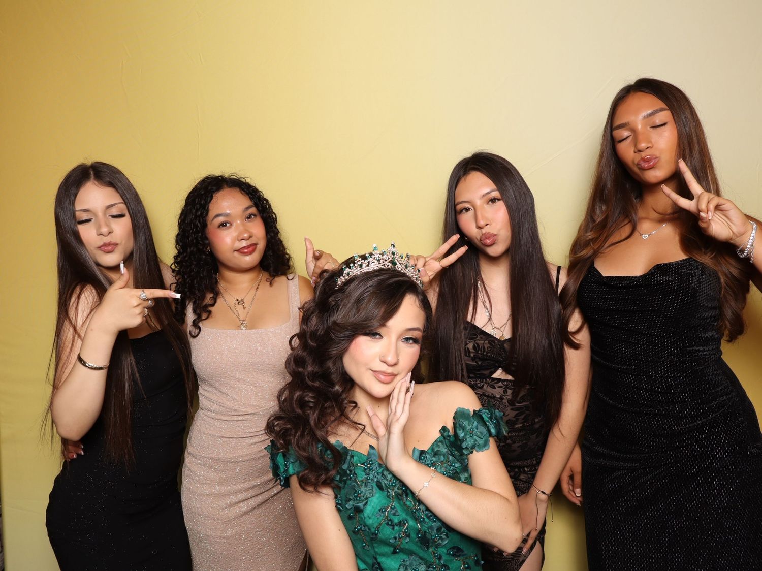 A group of friends pose playfully together at a formal event against a yellow backdrop.