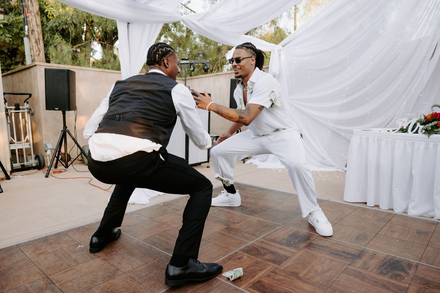 Two wedding guests dancing energetically on wooden dance floor.