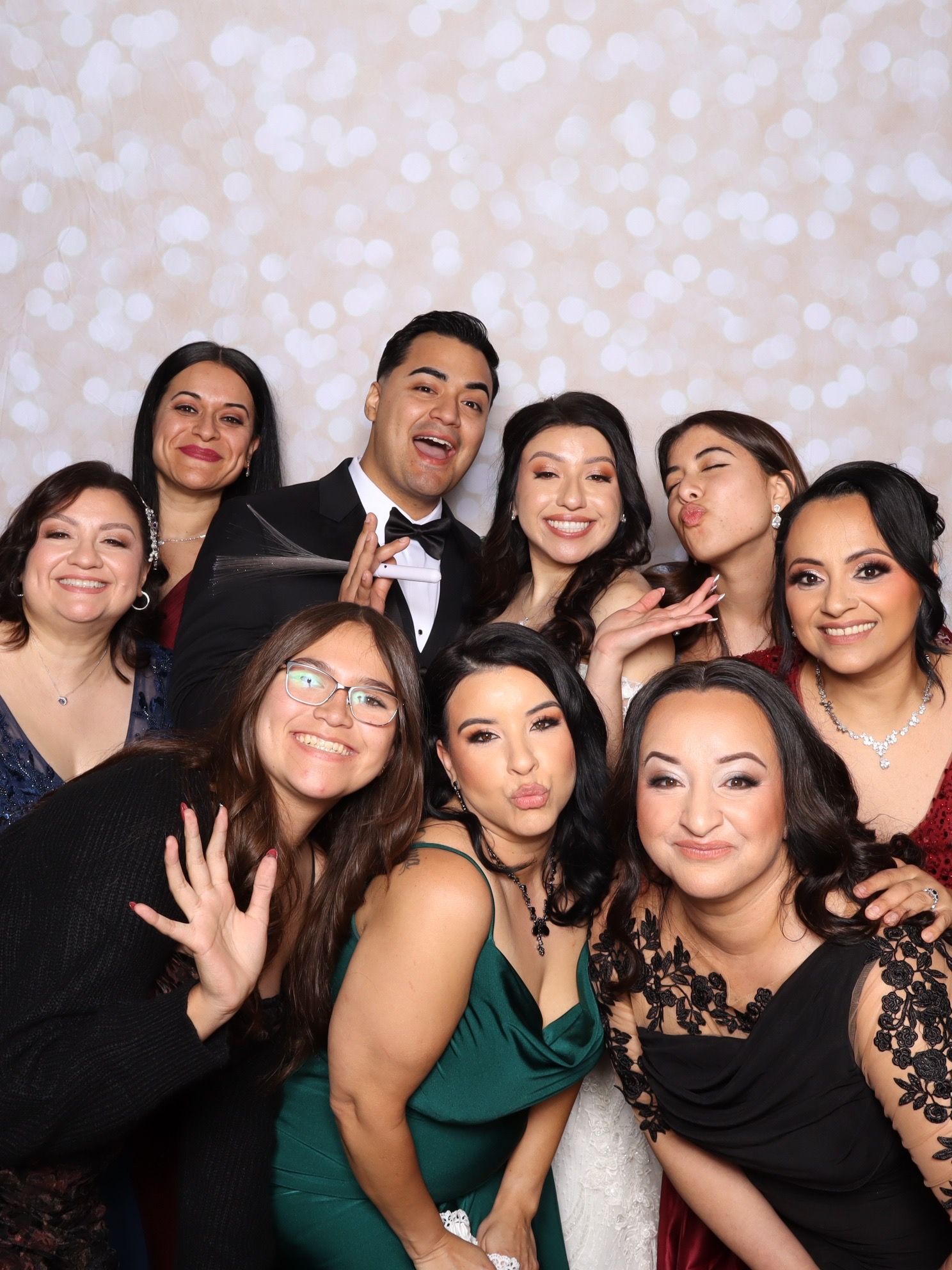 Group of friends posing together in a photo booth at a formal event, smiling and making fun faces.