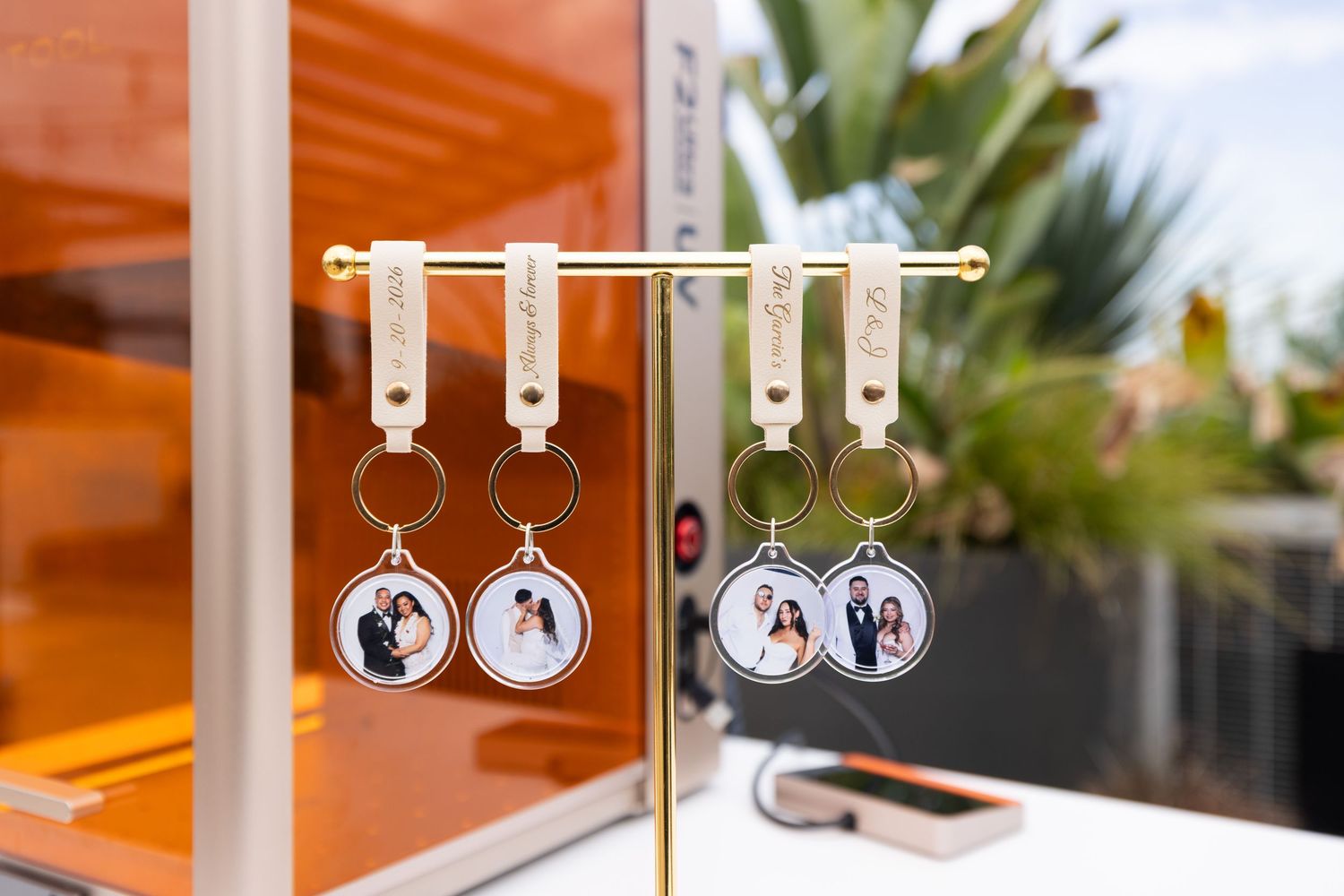Custom photo keychains displayed on a gold stand, featuring personalized couple portraits in round frames.