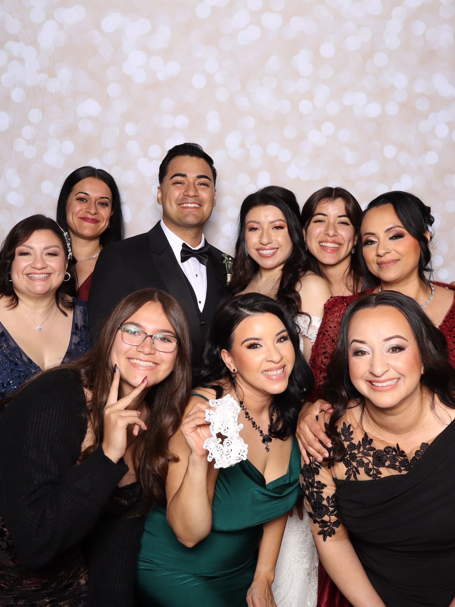 A group of friends pose together at a photo booth wearing formal attire in black and green dresses.