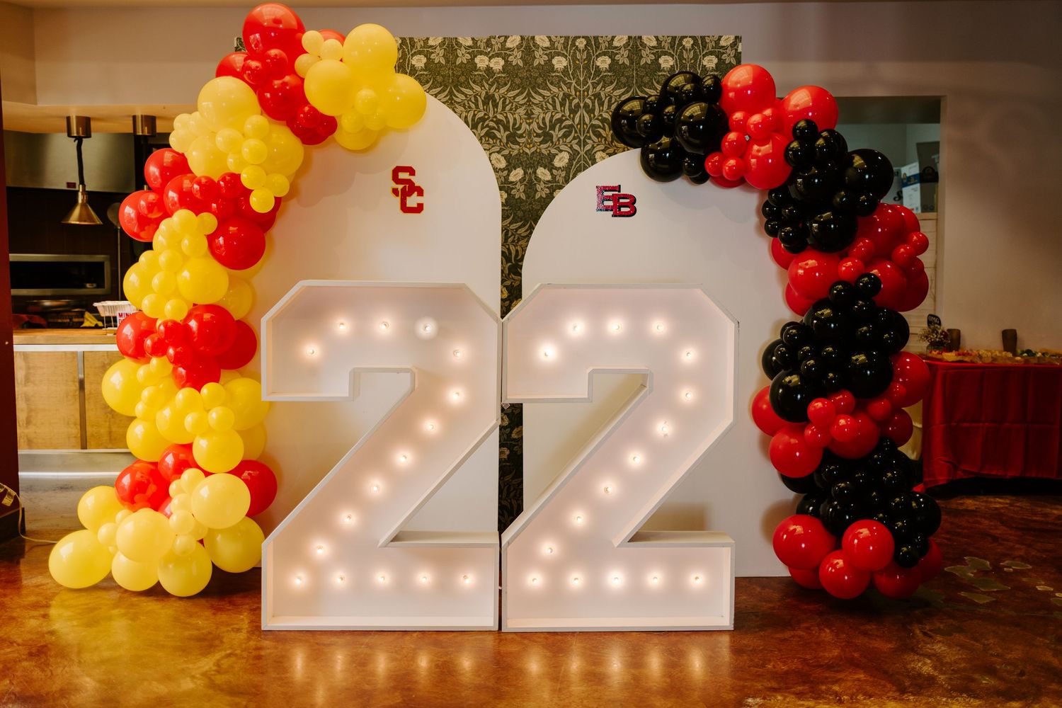 Illuminated number 22 display decorated with red, yellow and black balloon arch.