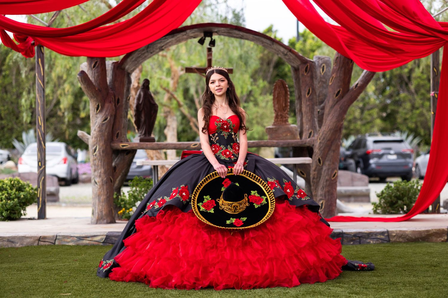 Stunning black and red ball gown photographed outdoors under red draped decorations.