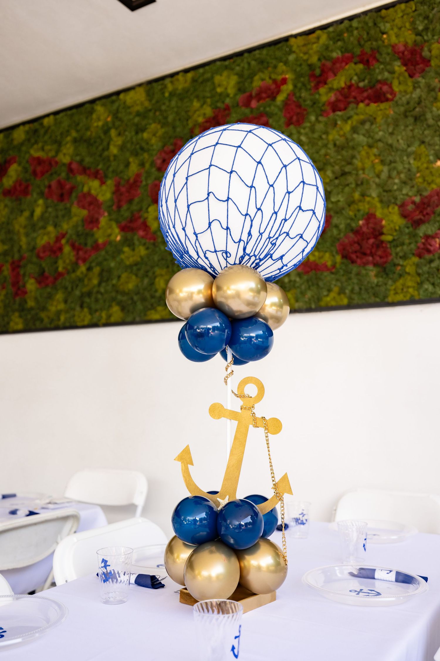 A balloon centerpiece with nautical anchor design in blue and gold colors.