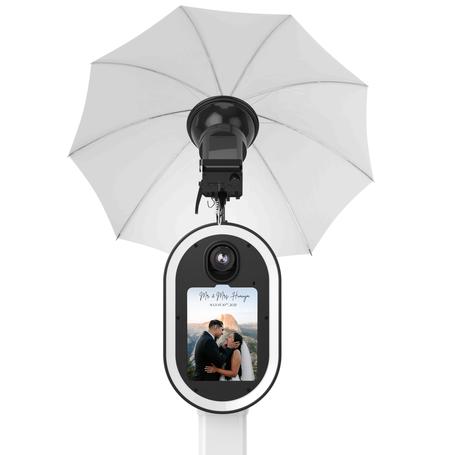 White photo booth kiosk with camera, display screen showing wedding couple, and white umbrella lighting on a stand.