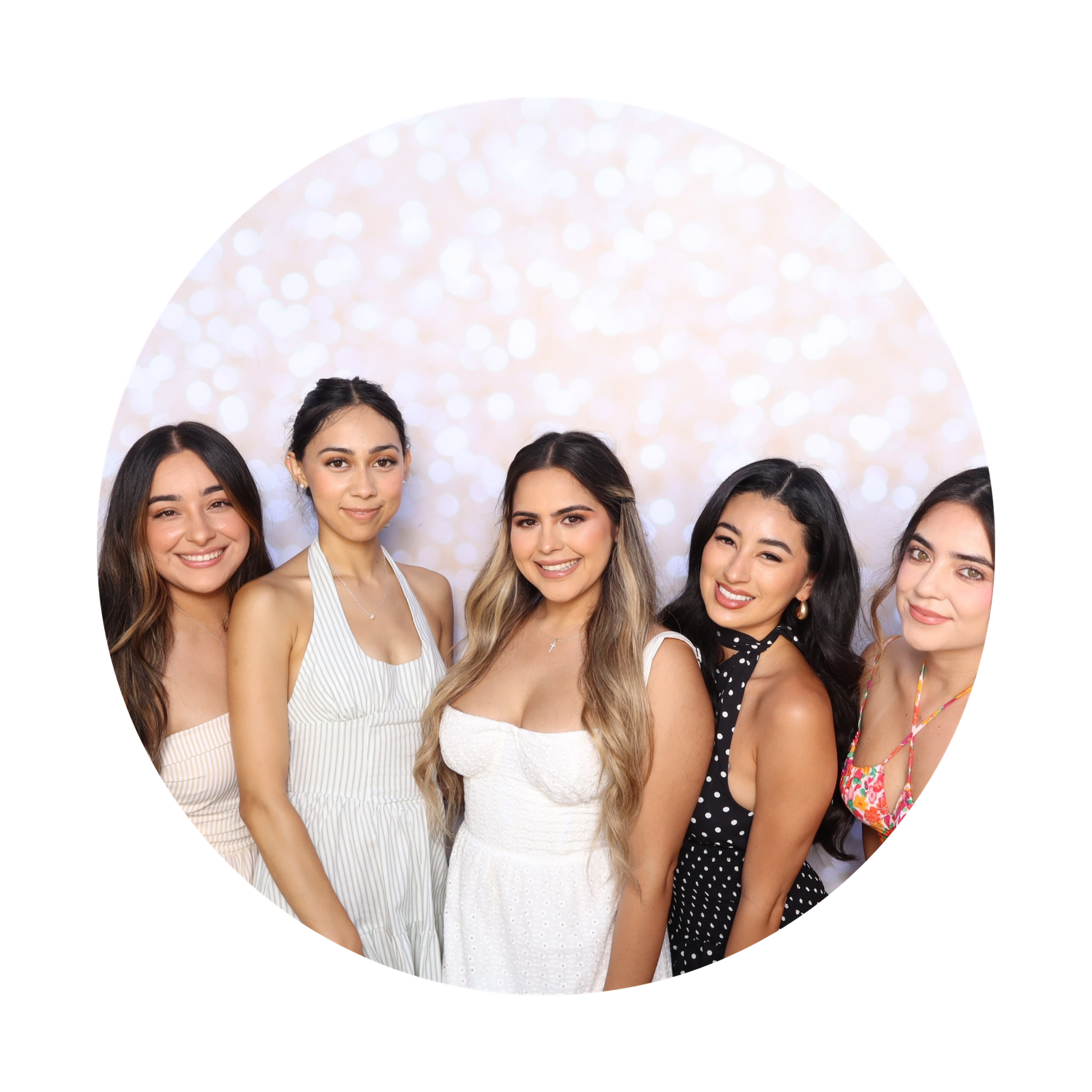 Five young women smiling together in front of a sparkly white bokeh backdrop at a formal event.