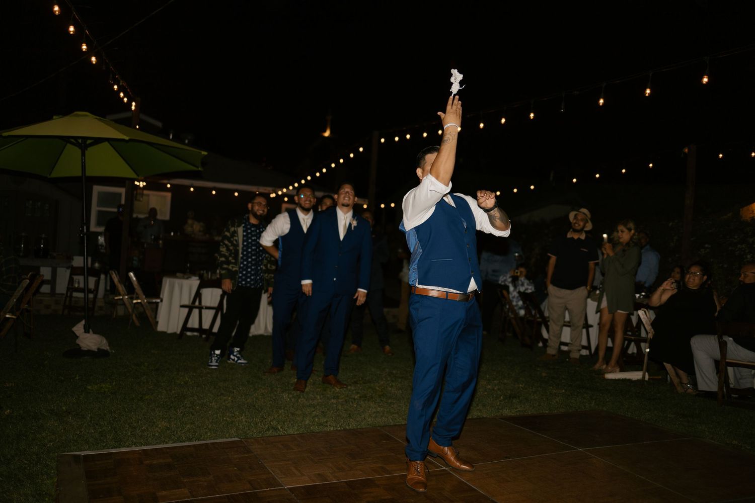 Guests celebrate on the dance floor at an outdoor evening wedding reception.