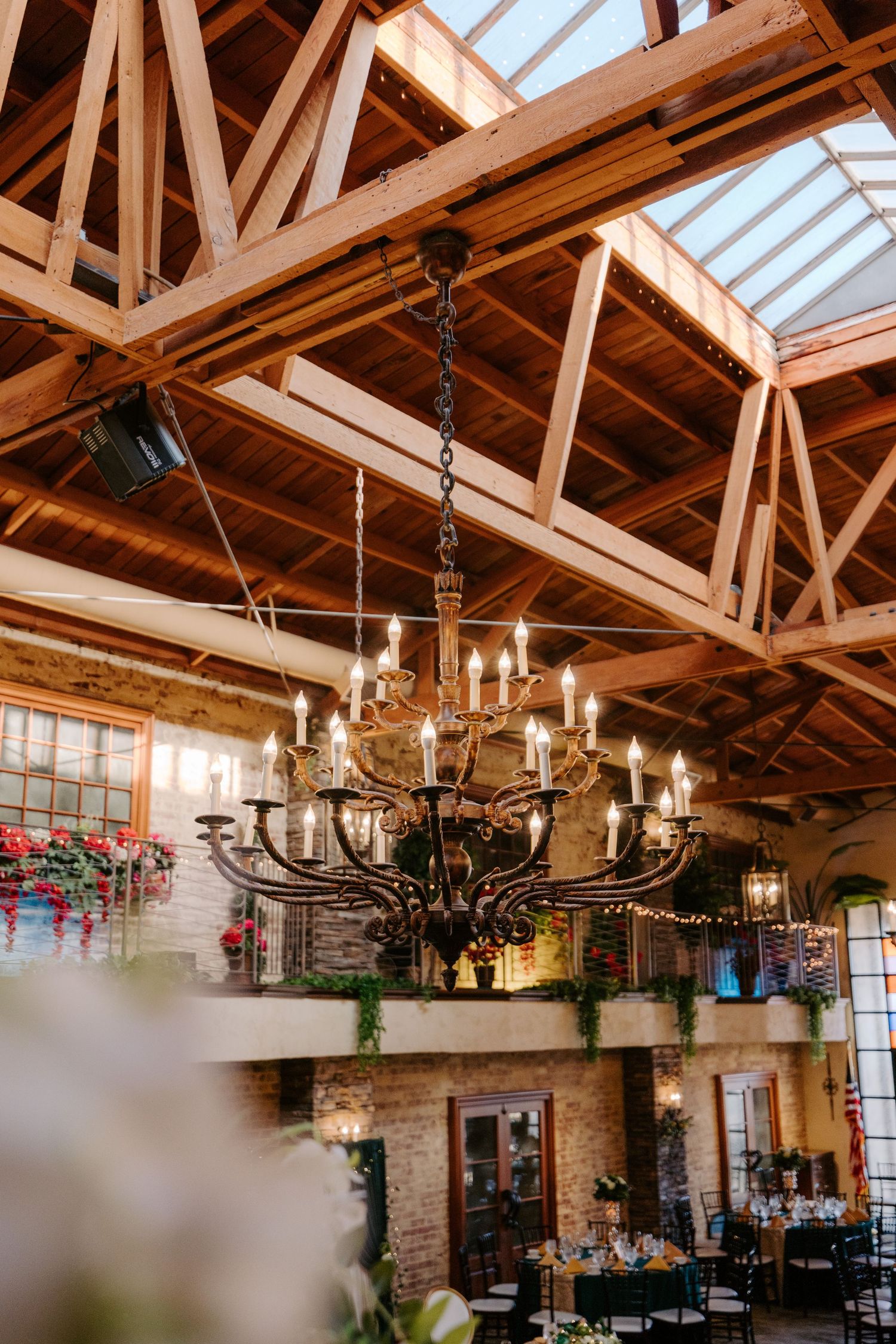 Rustic wooden beams and elegant chandeliers create a warm ambiance in a vintage-style venue interior.