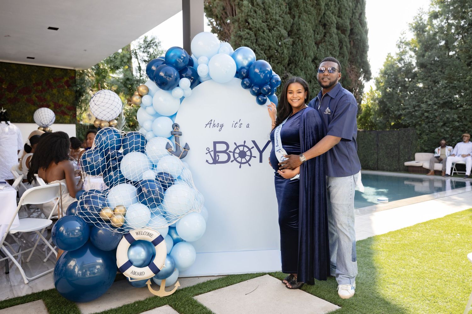 A nautical themed baby shower backdrop with blue and white balloon decorations.