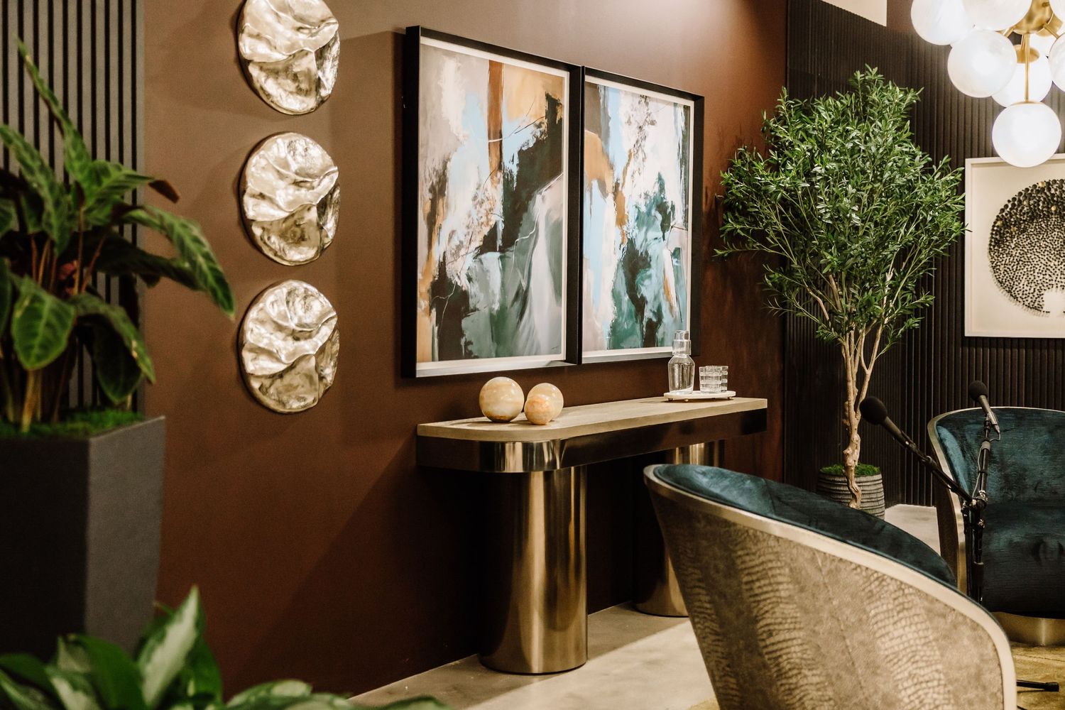 Elegant interior with gold console table, abstract artwork, and lush green plants.
