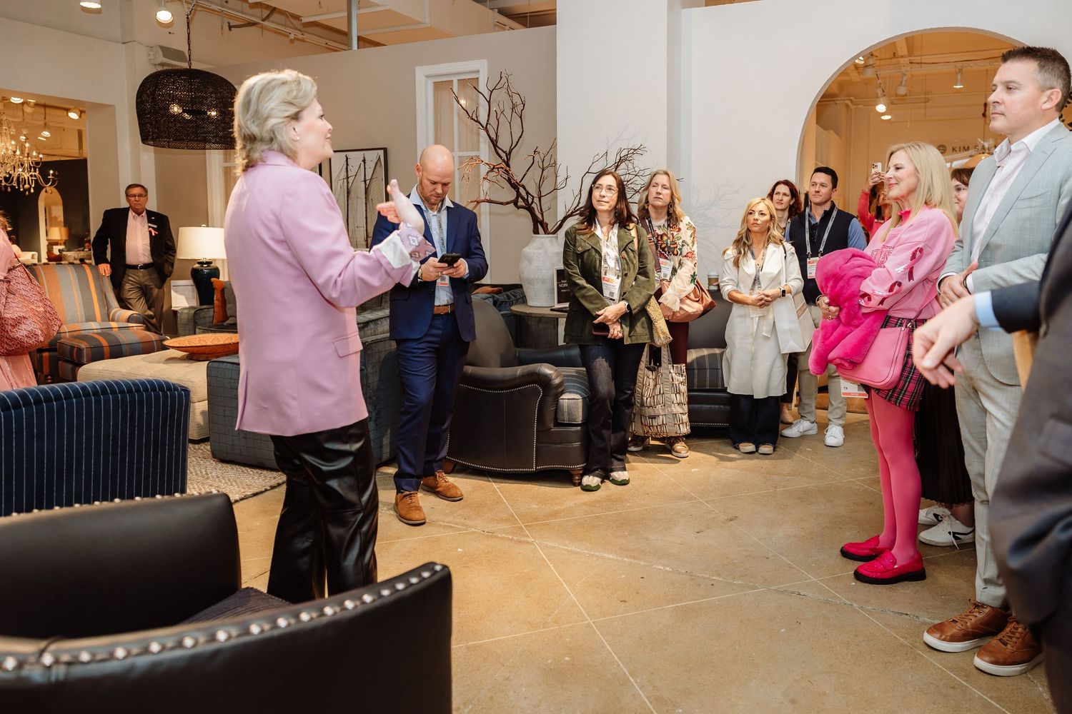 Interior design presenter addresses group of attendees in modern furniture showroom setting.