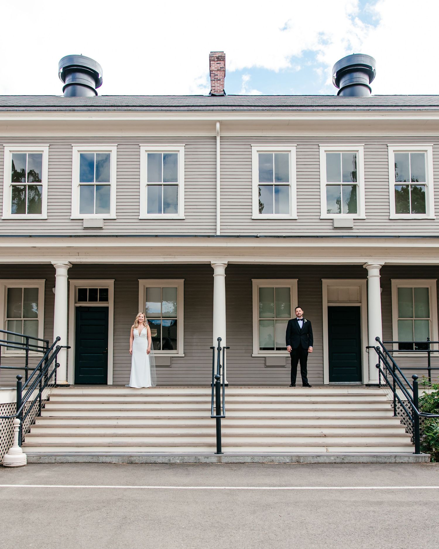 Bride and groom standing apart on steps of a classic colonial-style wedding venue.