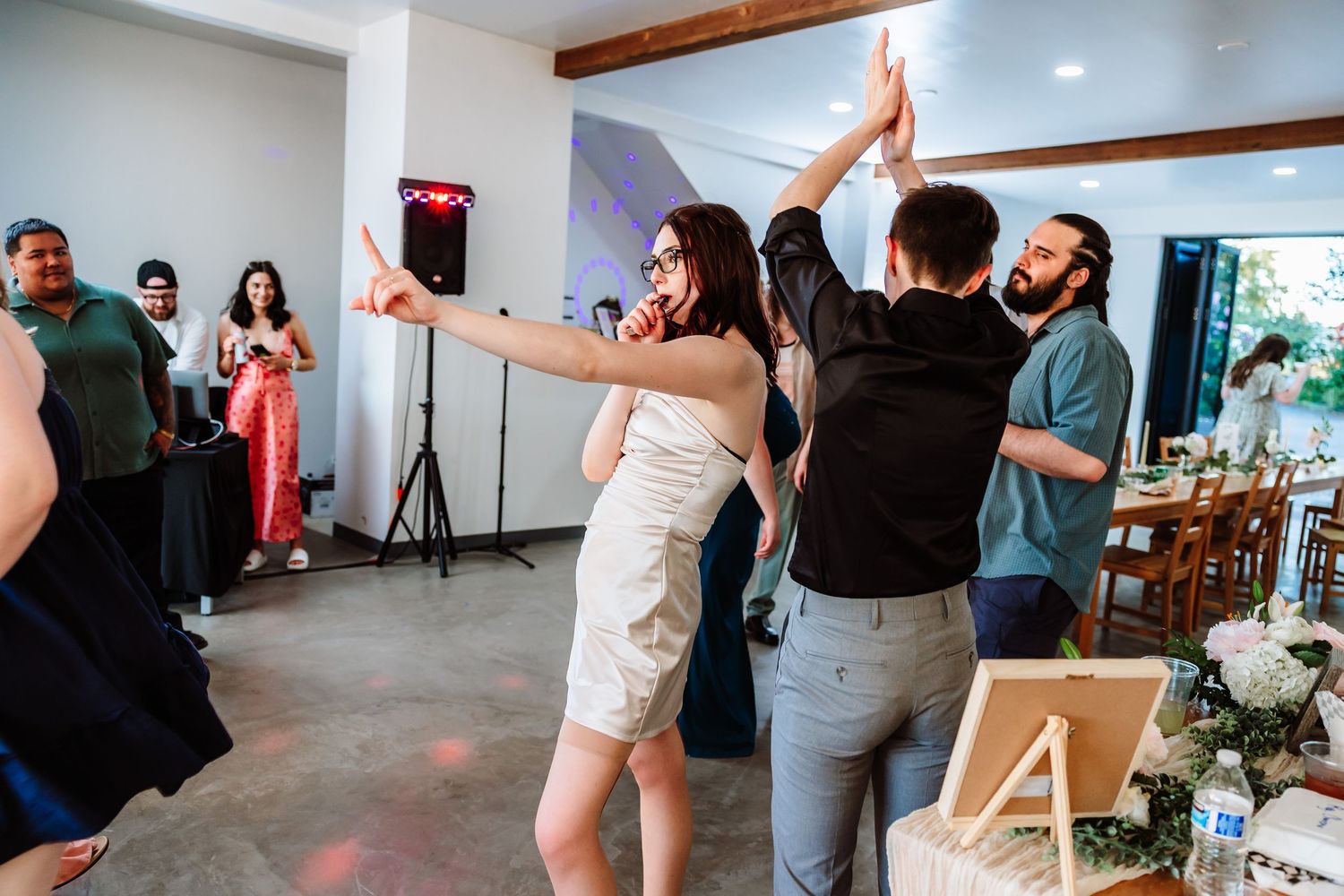 Wedding guests high-fiving and dancing energetically on the reception dance floor.