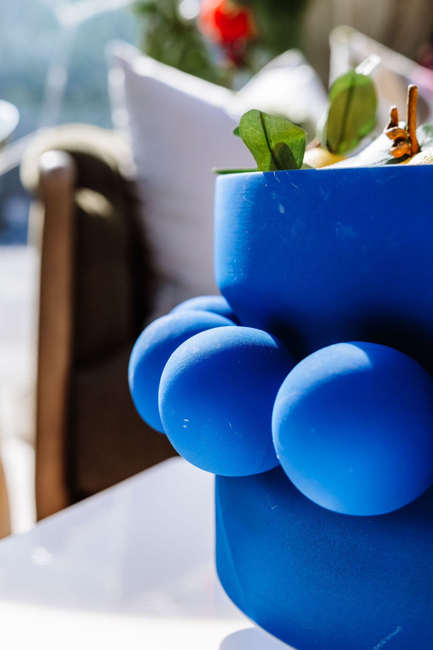 Close-up of a unique blue bubble-textured vase with green plant stems.