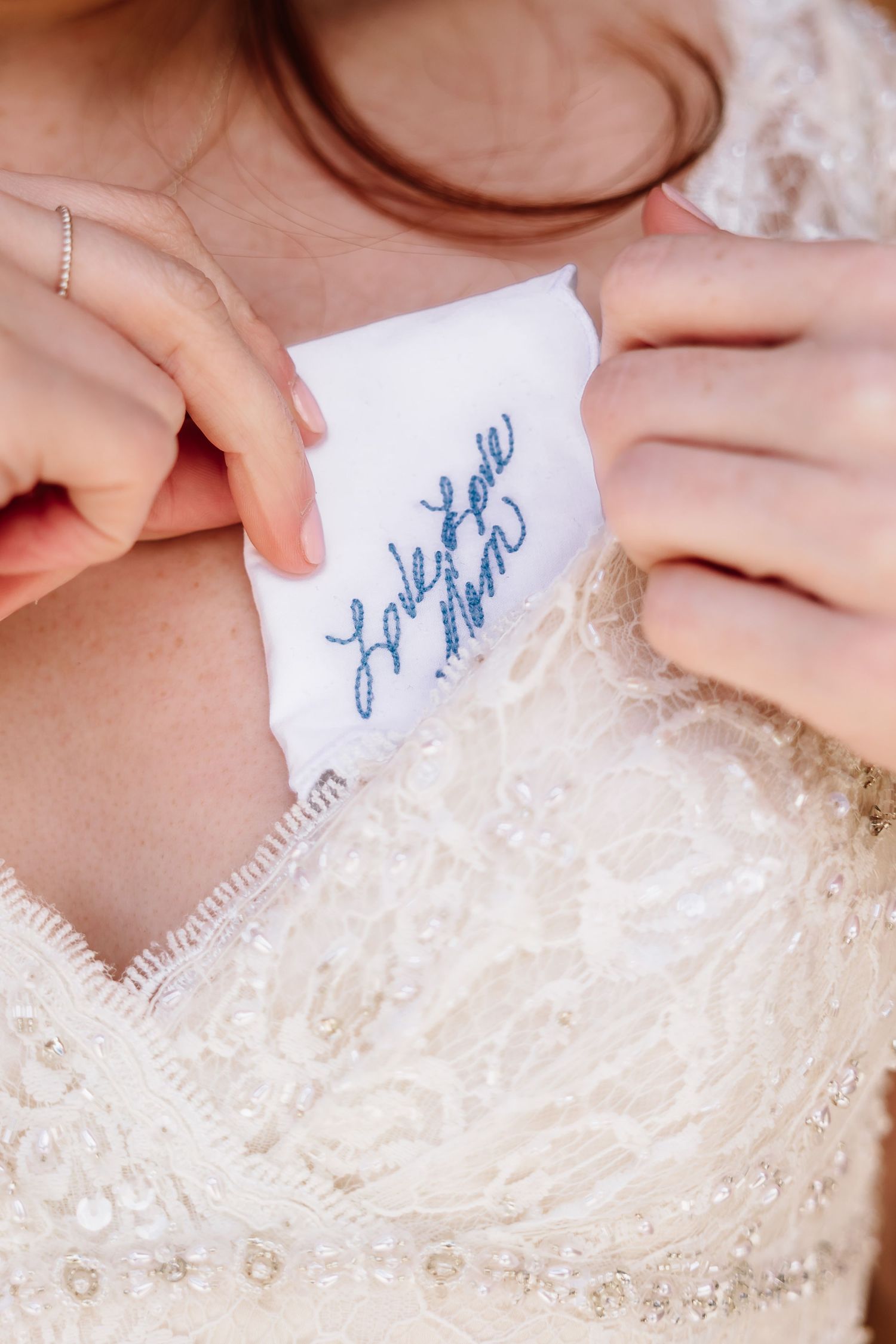 Bride revealing blue embroidered message on wedding dress label, a sentimental hidden detail.