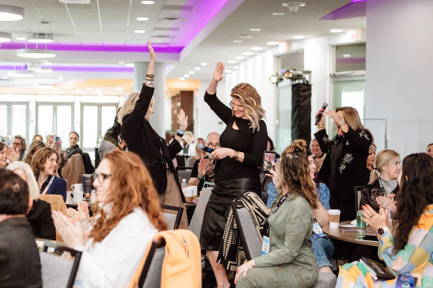 Excited attendees raising hands and celebrating at the Vacation Rental Design Summit.