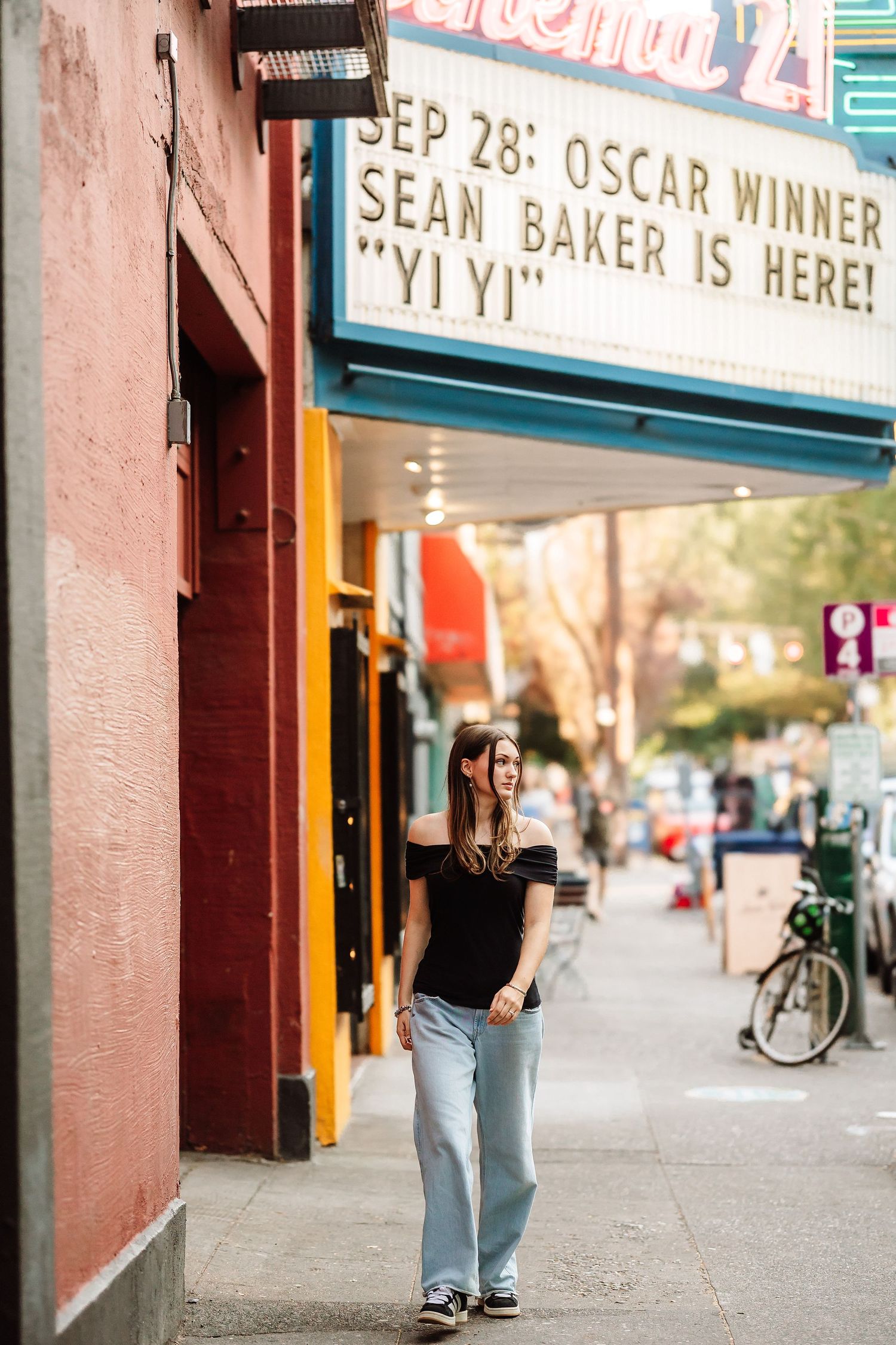 Woman walking under a movie theater marquee advertising Oscar Winner Sean Baker and Yi Yi on Sep 28.