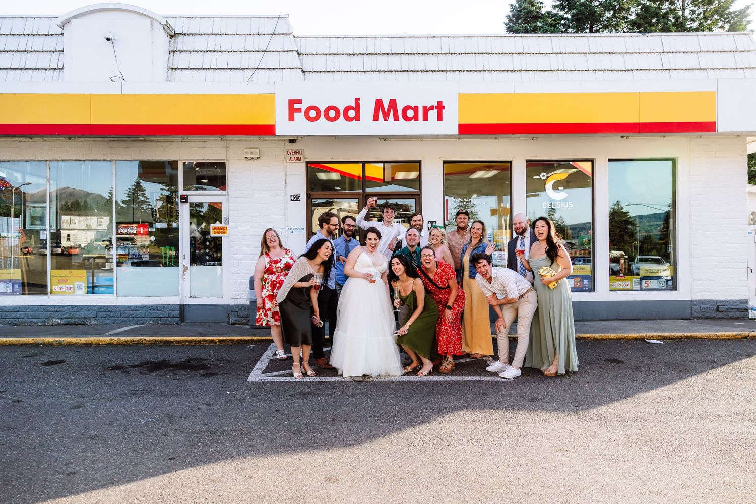 Wedding party group photo posing and smiling in front of a Food Mart convenience store.