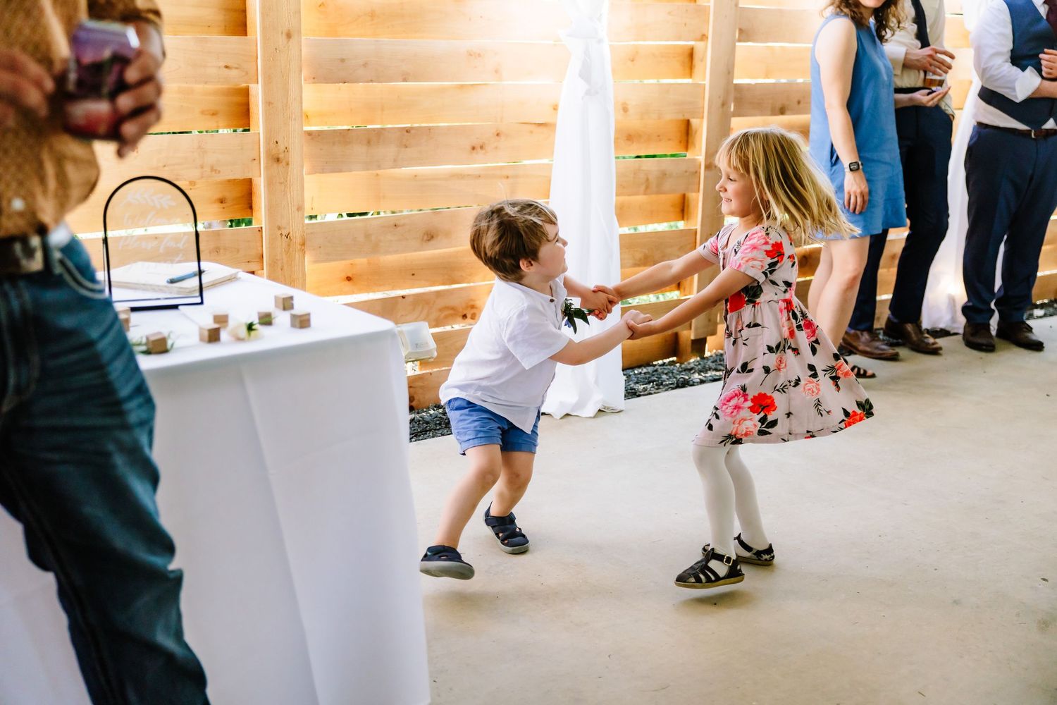 Two young children joyfully dancing and spinning together at a wedding reception.