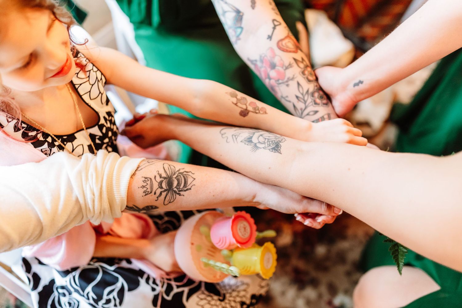 Group of people stacking tattooed arms together in a fun celebratory gesture.