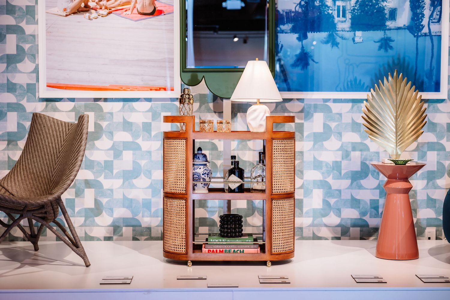 Stylish bar cart with bottles and lamp against a blue mosaic tile wall.