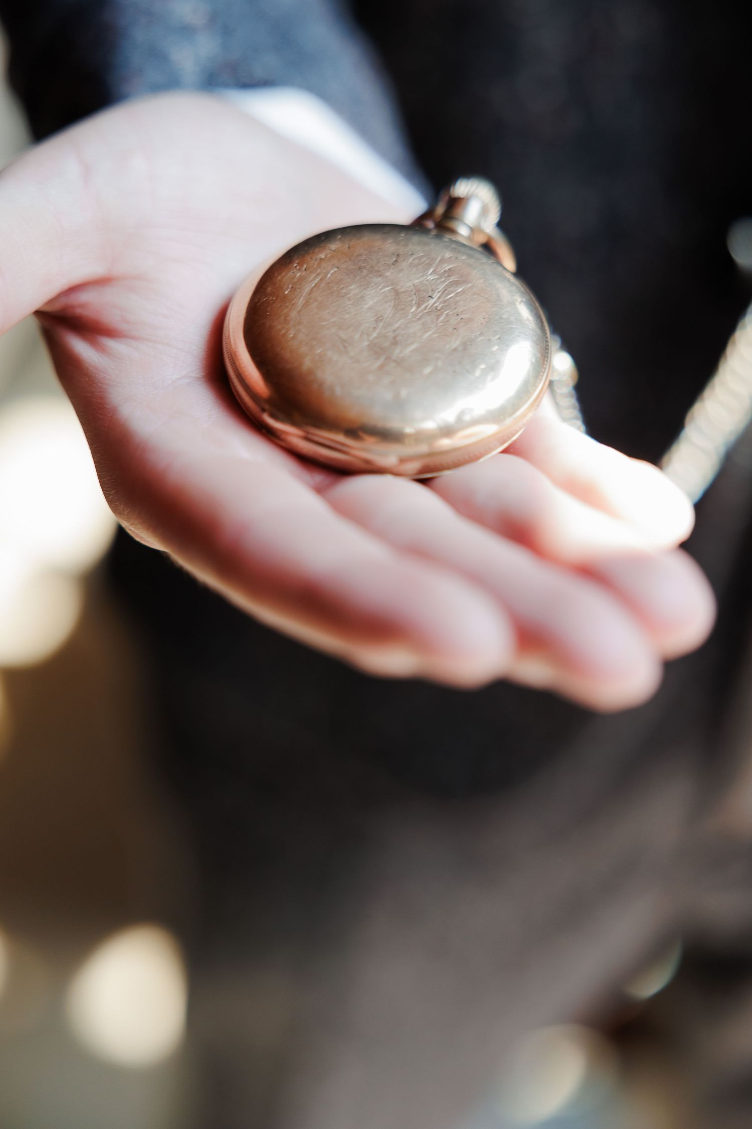 Groom holding a vintage silver pocket watch on his palm before the wedding ceremony.