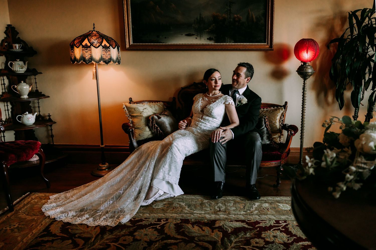 Bride and groom sit together in a warmly lit vintage-styled wedding portrait.
