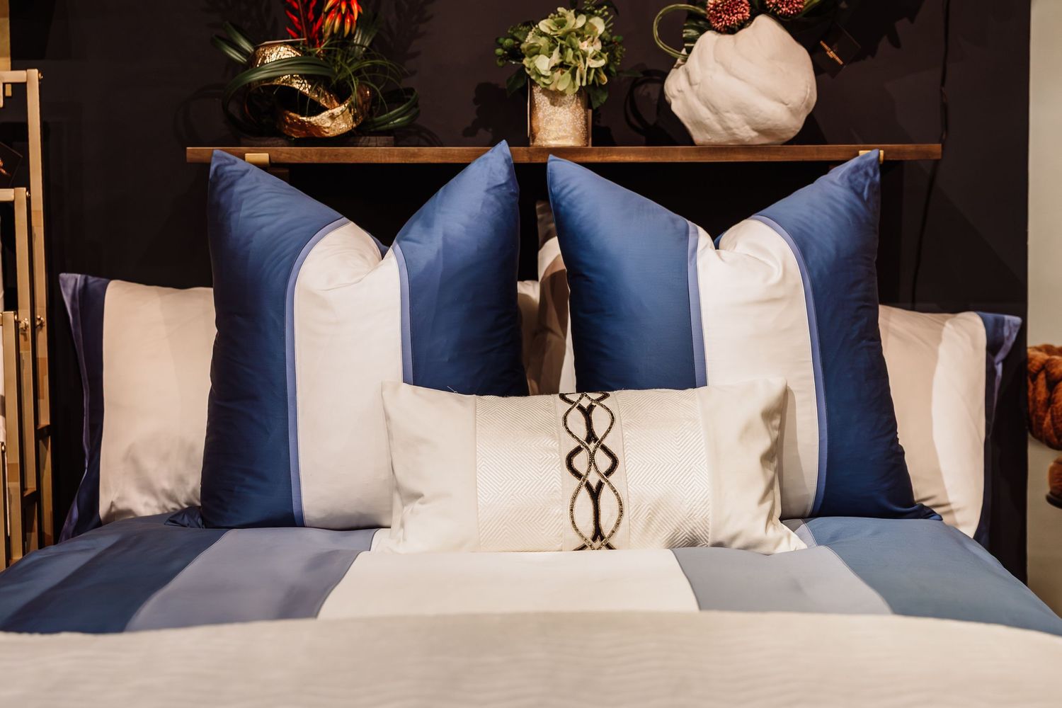 Blue and white decorative throw pillows arranged on a bed with elegant bedding.