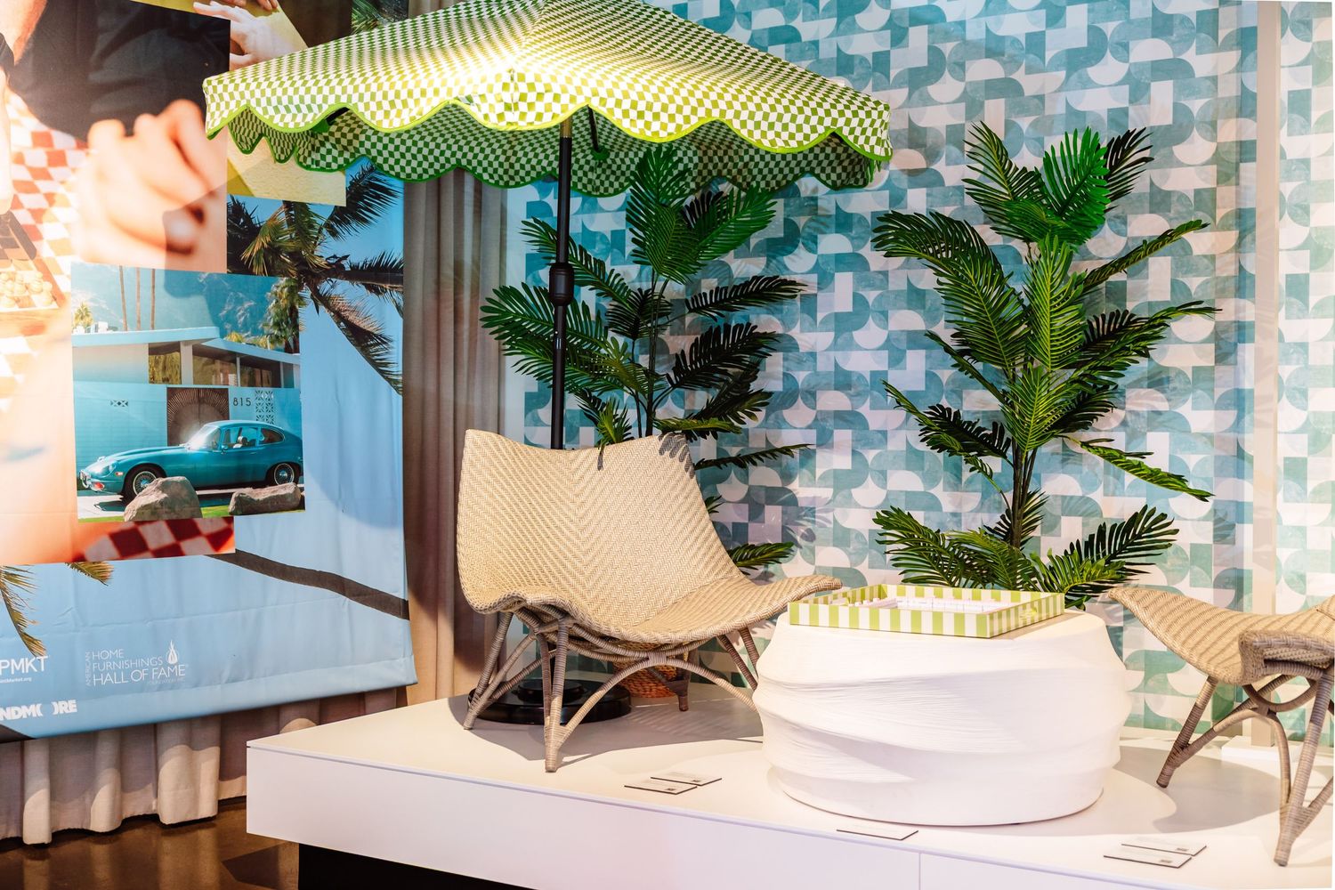 Tropical-themed interior display with wicker chair, palm plants, and striped umbrella.