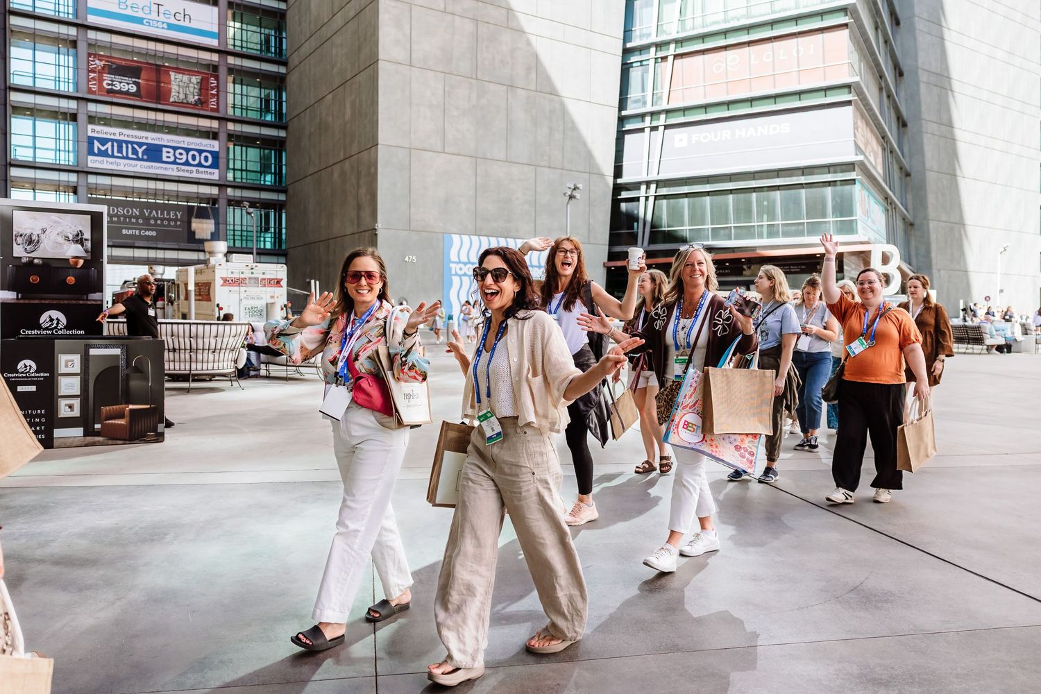 Group of women walking outside modern convention center carrying tote bags at professional conference.