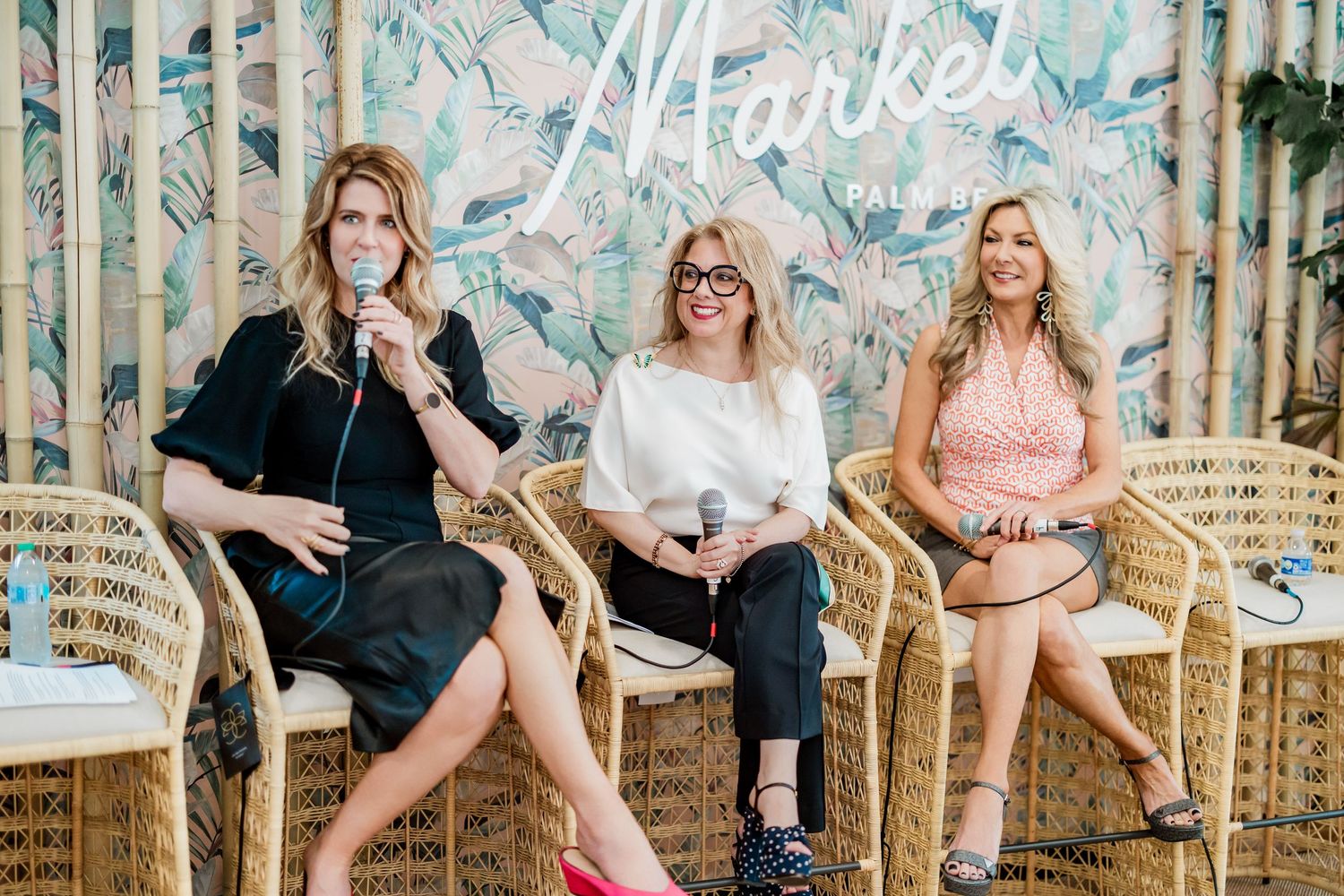 Three women seated in rattan chairs speaking at a Market Fall panel event with tropical backdrop.