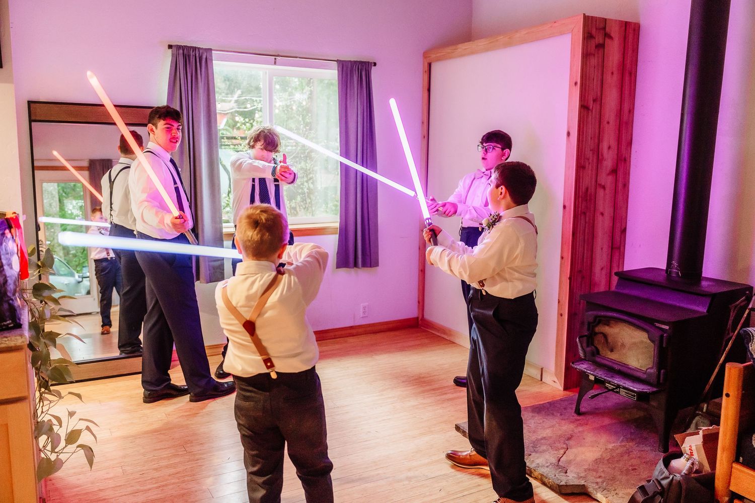 Groomsmen having fun with colorful lightsabers in a room before a Star Wars themed wedding.