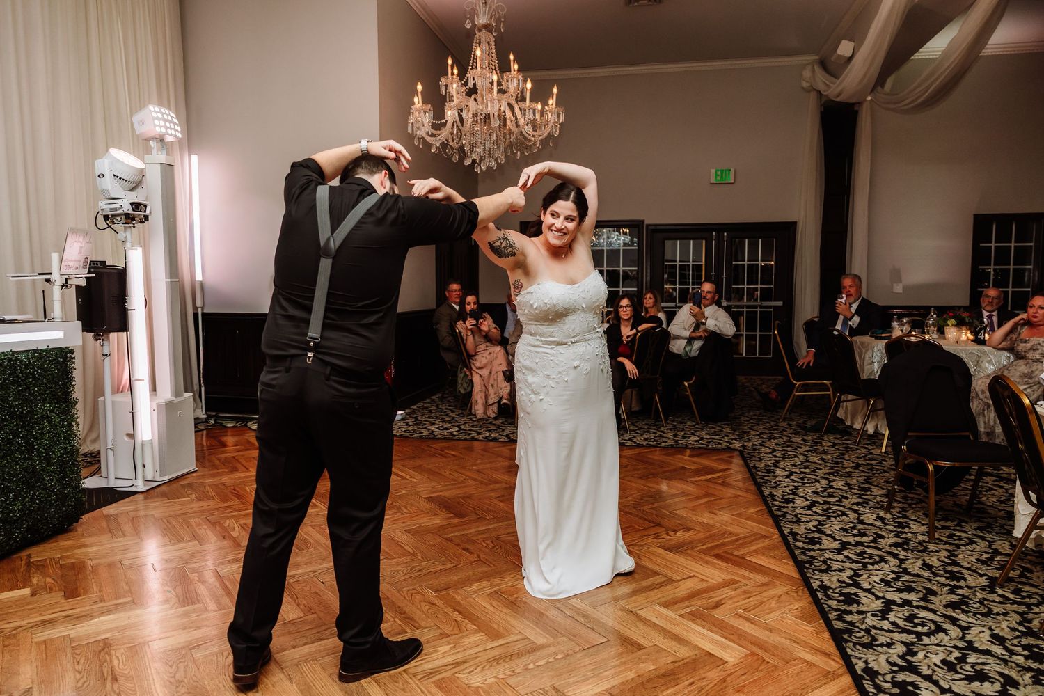 Bride and groom share romantic first dance under a chandelier at their elegant wedding reception.