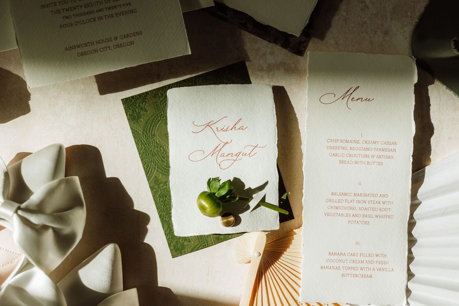 Elegant wedding stationery flat lay featuring invitation cards, menu, and floral accents in soft neutral tones.