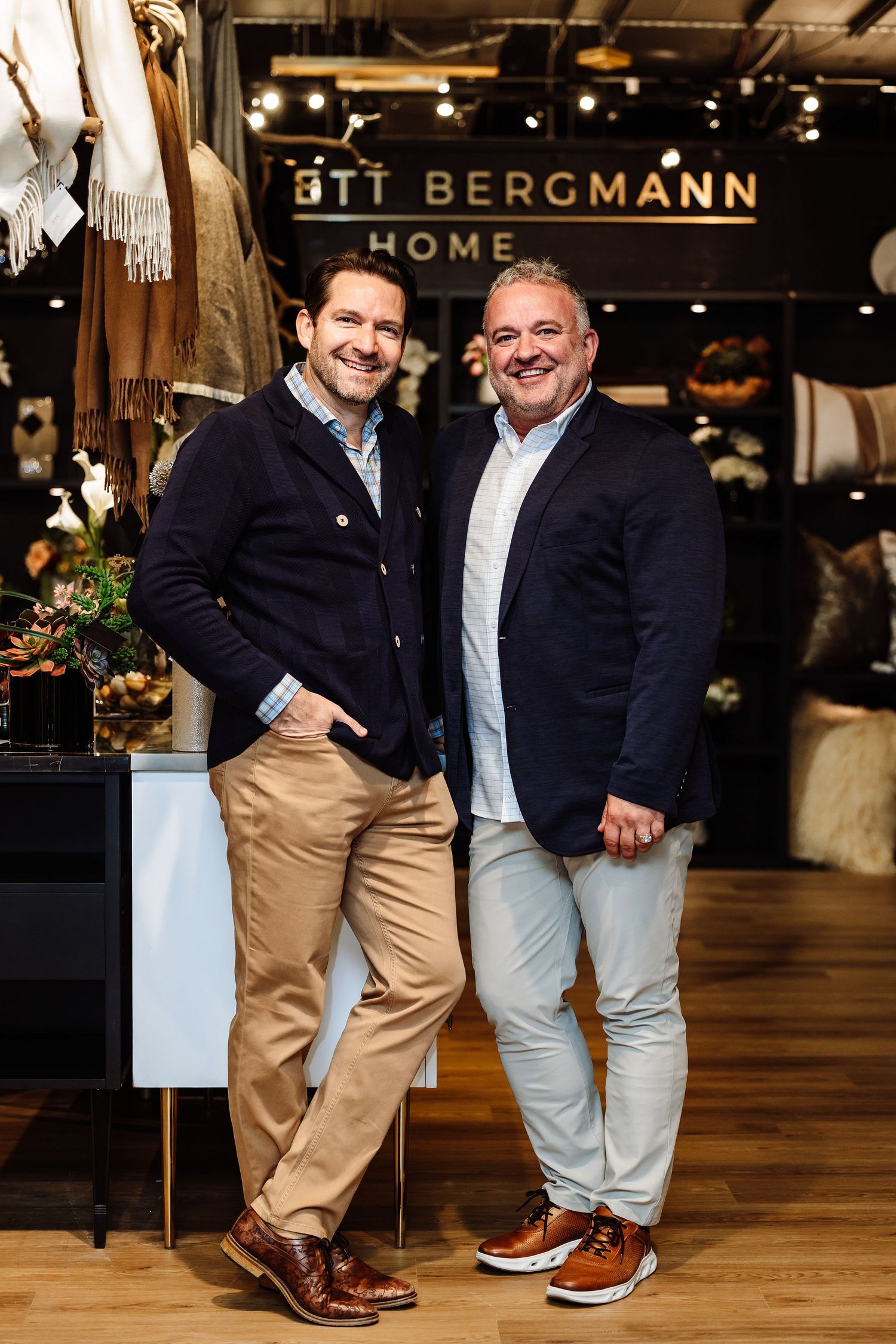 Two smiling men in blazers posing together inside Ott Bergmann Home store.