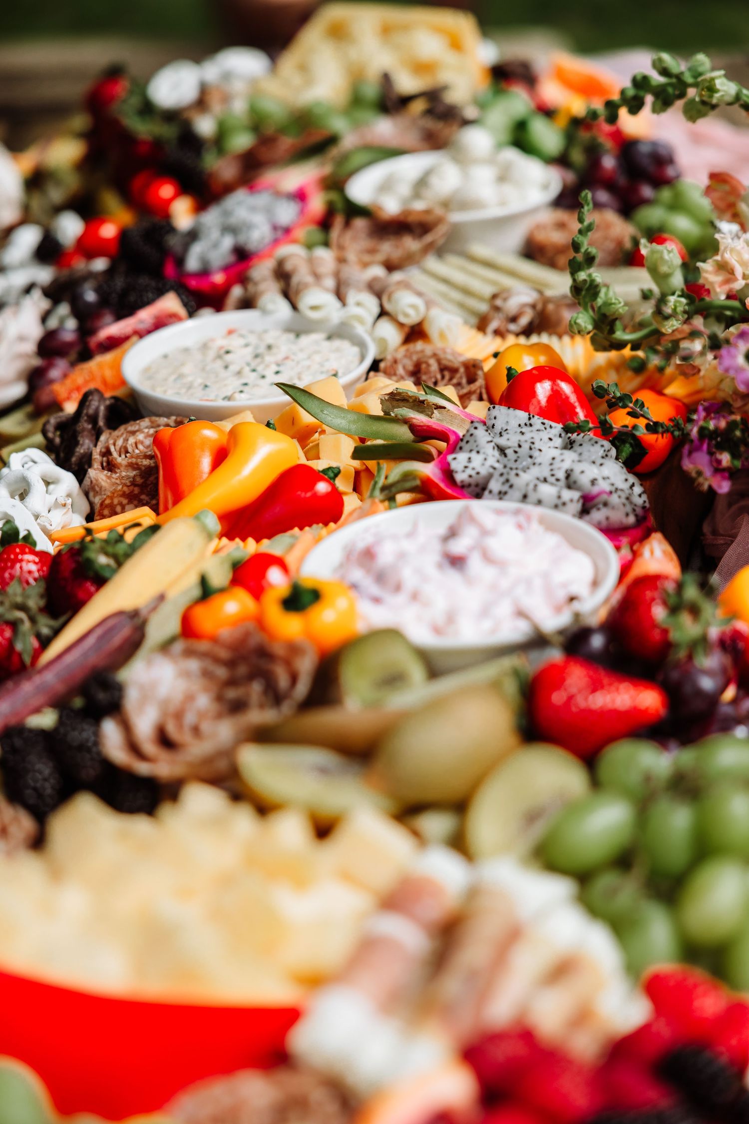 Abundant wedding grazing table filled with fruits, vegetables, cheeses, dips, and charcuterie in colorful arrangement.