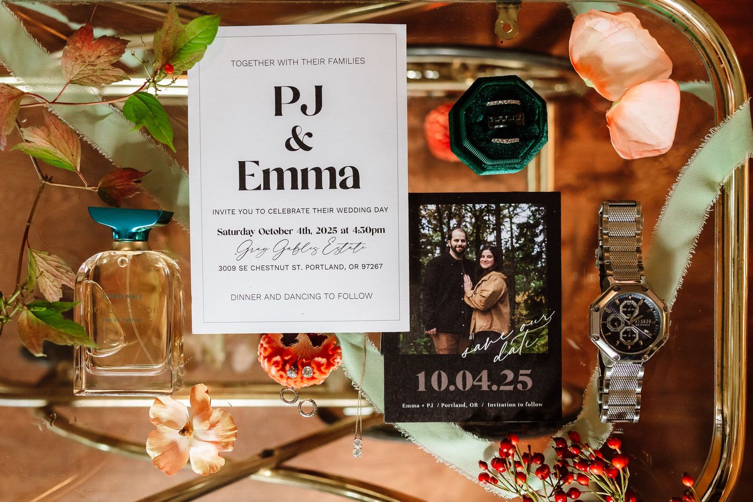 Wedding invitation suite for PJ and Emma displayed on a mirrored tray with florals, a watch, and cologne on October 4, 2025.
